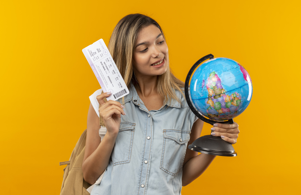viagem segura para europa- moça segurando uma passagem e um globo